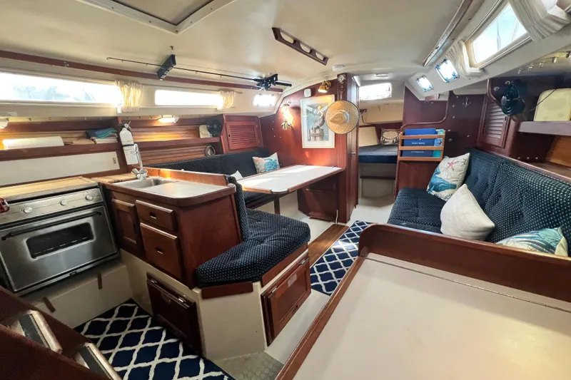 Slide: The Image of 1987 Catalina 30 MkII yacht interior with cozy seating, kitchen, and nautical decor. - 23