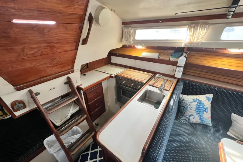 Slide: The Image of 1987 Catalina 30 MkII yacht interior with kitchen, sink, stove, and cozy seating area. - 26