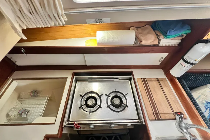 Slide: The Image of Catalina 30 MkII 1987 yacht kitchen with stove, cutting board, and storage shelves. - 28