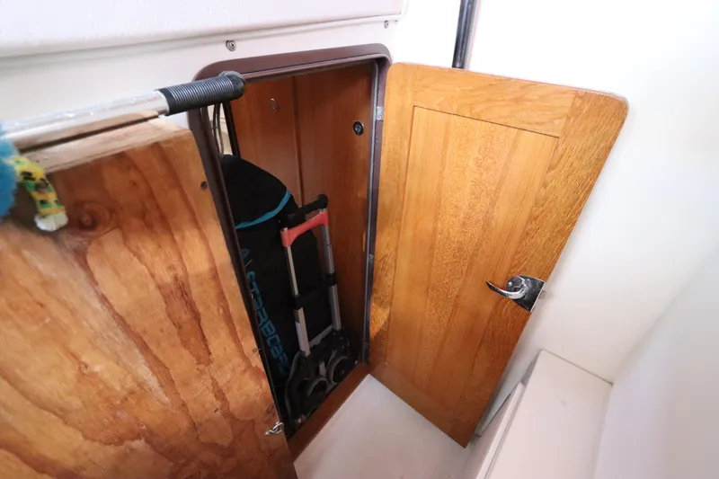 Slide: The Image of Wooden storage compartment on a 2007 Catalina Morgan 440 sailboat, containing a folded ladder. - 83