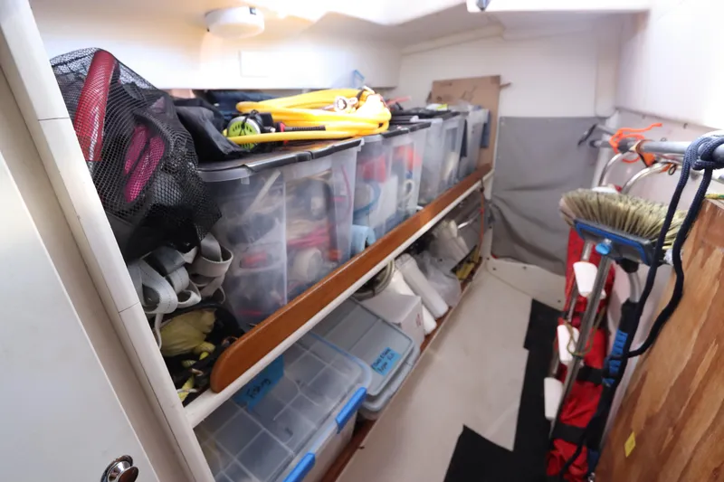 Slide: The Image of Storage area in a 2007 Catalina Morgan 440 sailboat, featuring organized bins and cleaning tools. - 85