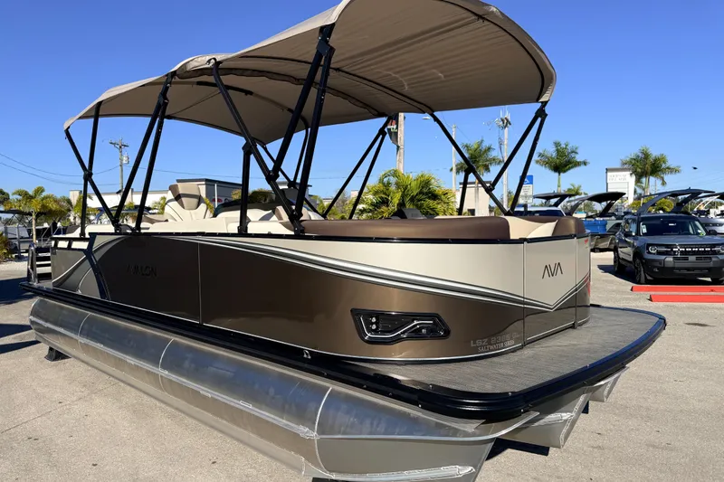 Slide: The Image of 2026 Avalon 2385 LSZ Quad Lounger Tri Toon boat with canopy, parked outdoors. - 4