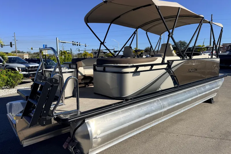 Slide: The Image of 2026 Avalon 2385 LSZ Quad Lounger Tri Toon boat with canopy, parked outdoors. - 5