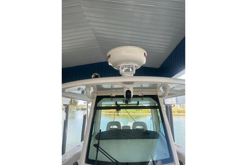 Slide: The Image of 2016 Boston Whaler 330 Outrage boat with radar, docked under a metal roof. - 5