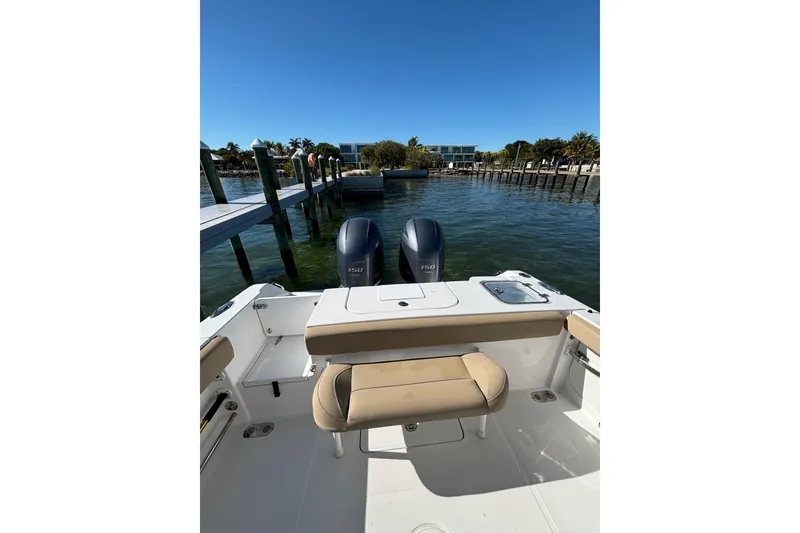 Slide: The Image of 2018 Sea Hunt Gamefish 25 boat with dual engines docked by a scenic waterfront. - 13