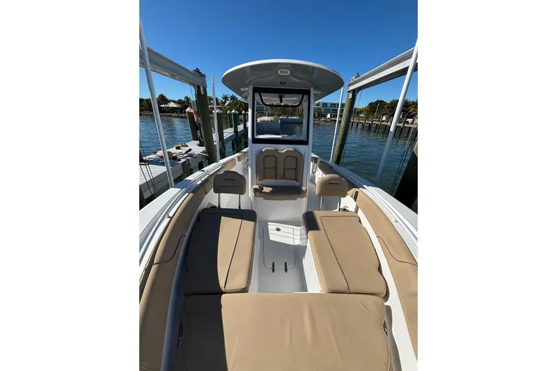 Slide: The Image of 2018 Sea Hunt Gamefish 25 boat interior with tan seating, docked by the water. - 6