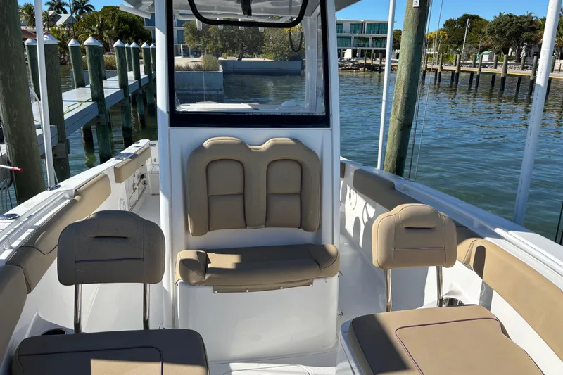 Slide: The Image of 2018 Sea Hunt Gamefish 25 boat interior with tan seating, docked by the water. - 7
