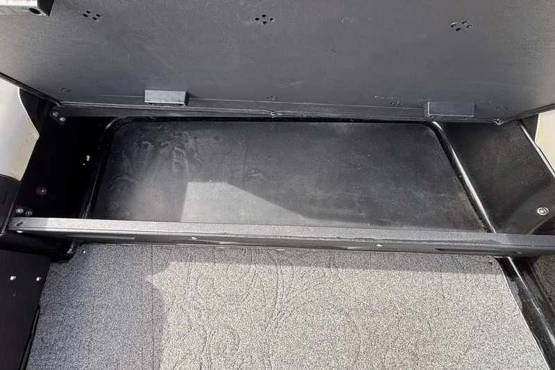 Slide: The Image of Open storage compartment in 2012 Axis A22 boat, featuring a black interior and gray carpet. - 11