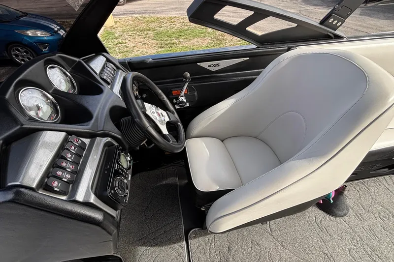 Slide: The Image of 2012 Axis A22 boat interior with steering wheel, dashboard, and white captain's seat. - 22