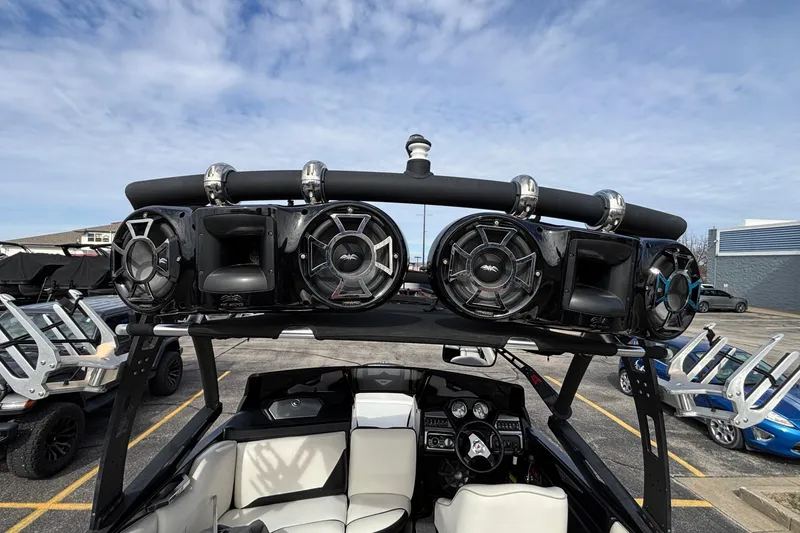 Slide: The Image of 2012 Axis A22 boat with mounted speakers and wakeboard racks, parked under a clear sky. - 33