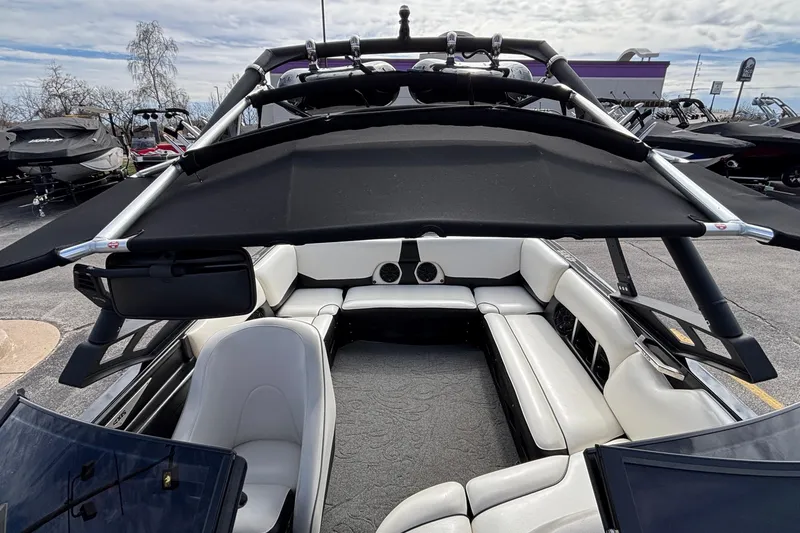 Slide: The Image of 2012 Axis A22 boat interior with white seating and black canopy, parked outdoors. - 6