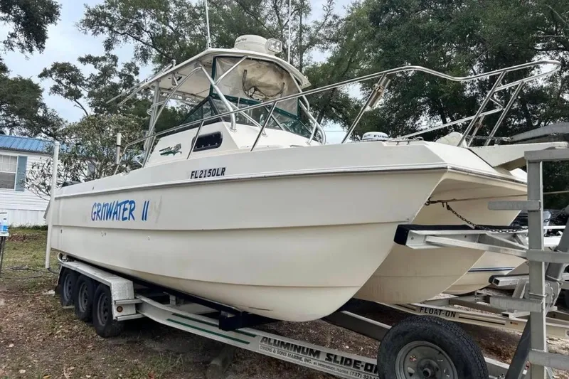 Slide: The Image of 1997 Sea Cat SL5C boat on trailer, named "Grinwater II," parked outdoors. - 3