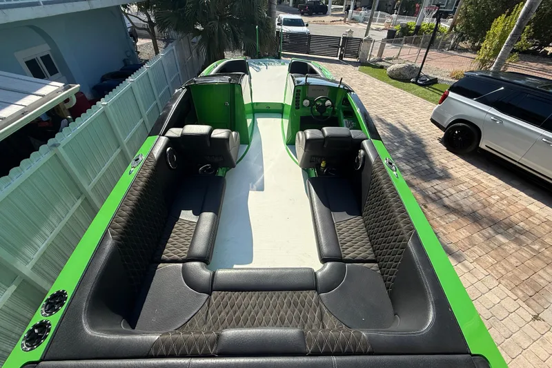 Slide: The Image of 2021 E-Ticket 29 boat with green accents and black quilted seating, parked on a driveway. - 21