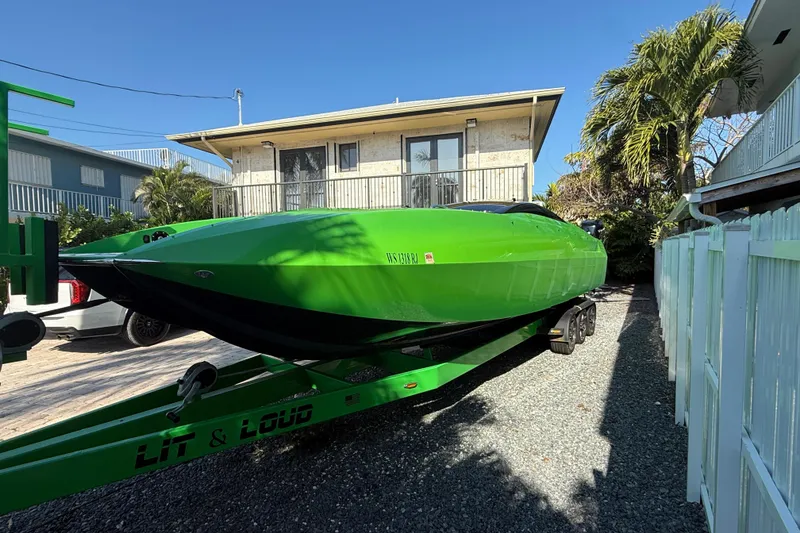 Slide: The Image of Green 2021 E-Ticket 29 boat on trailer, parked near a house with palm trees. - 9