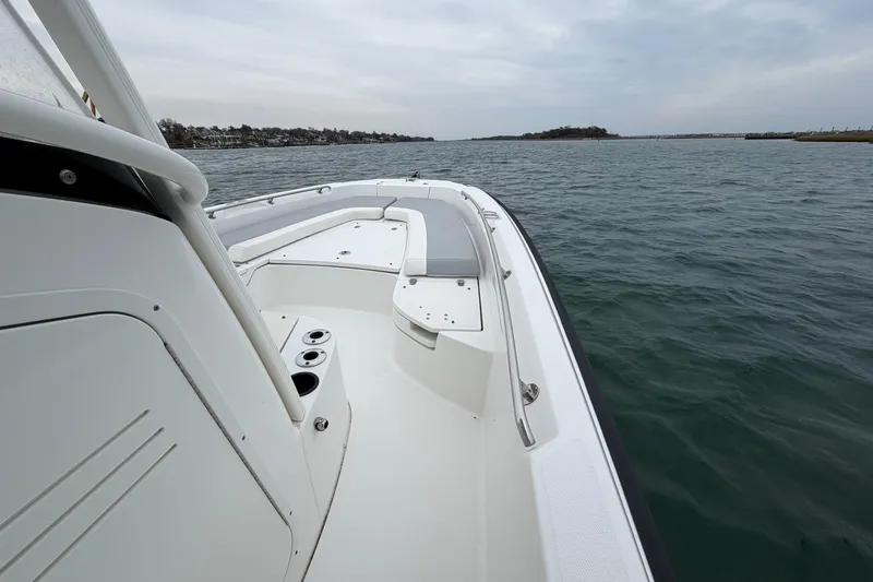 Slide: The Image of 2016 Boston Whaler 240 Dauntless boat on calm water, showcasing spacious deck and seating. - 21