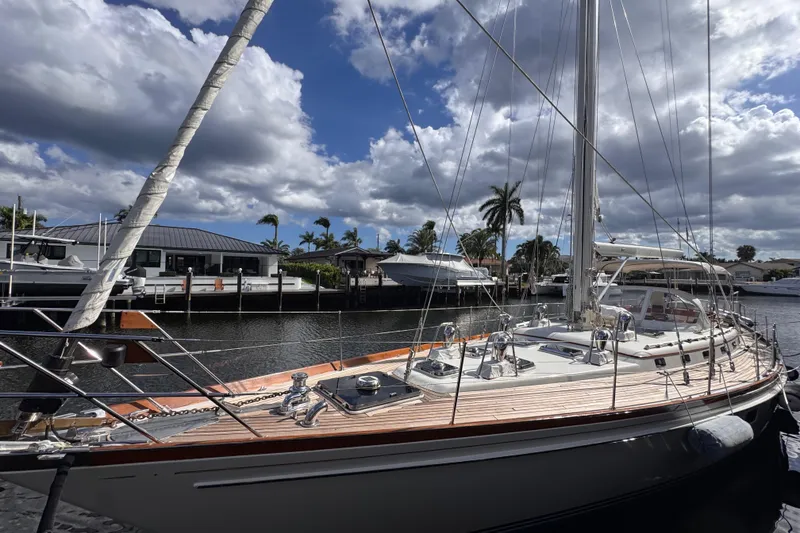 Slide: The Image of 1989 Little Harbor Sloop 58' docked, showcasing elegant design and craftsmanship under a partly cloudy sky. - 105