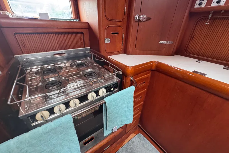 Slide: The Image of Galley kitchen in 1989 Little Harbor Sloop, featuring a four-burner stove and wooden cabinetry. - 56