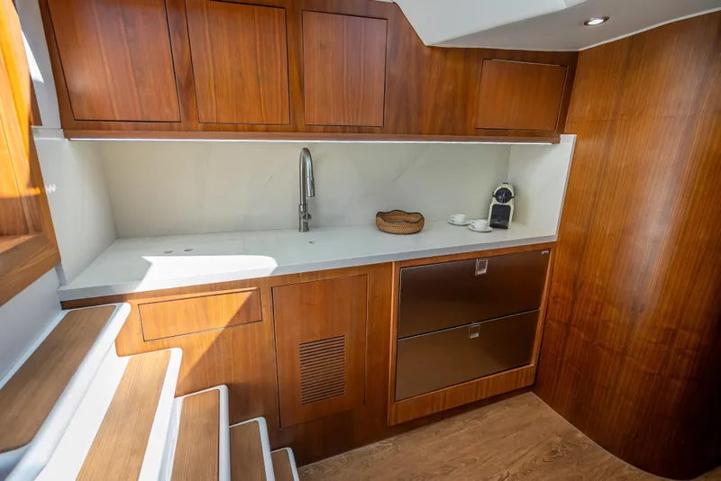 Slide: The Image of Luxurious 2025 Rybovich Custom Margaritavich yacht interior with modern wooden cabinetry and sleek kitchenette. - 21