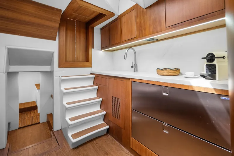 Slide: The Image of Modern yacht interior with wooden cabinetry, sleek countertops, and compact appliances in Rybovich Custom Margaritavich 2025. - 23