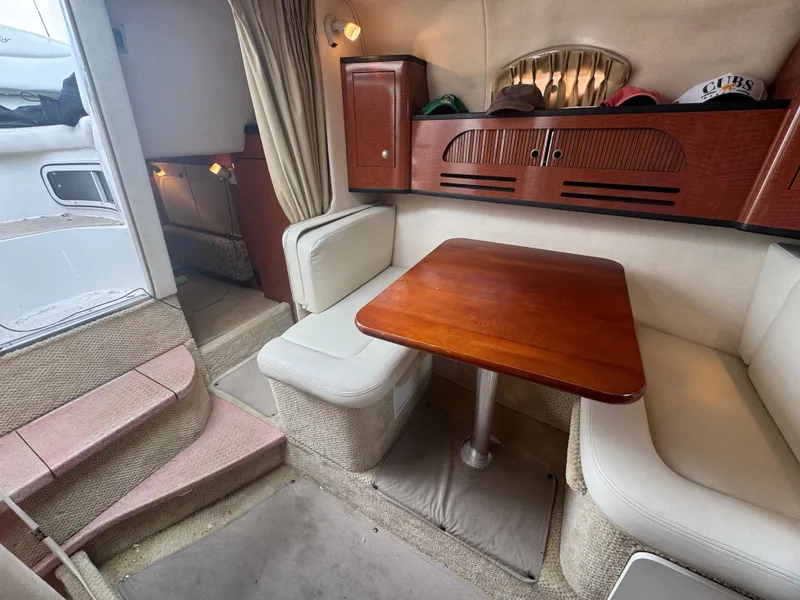 Slide: The Image of The cabin of a 2005 Sea Ray Sundancer 280 features a cozy seating area with a wooden table. - 9