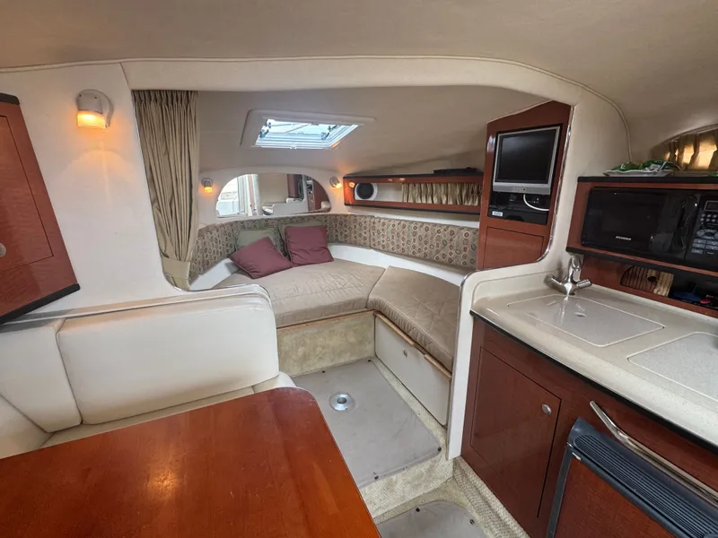 Slide: The Image of Interior of a 2005 Sea Ray Sundancer 280 with cozy seating area, table, and kitchenette. - 6