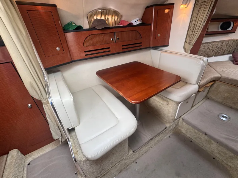 Slide: The Image of The interior of a 2005 Sea Ray Sundancer 280 features a cozy seating area with a wooden table. - 8