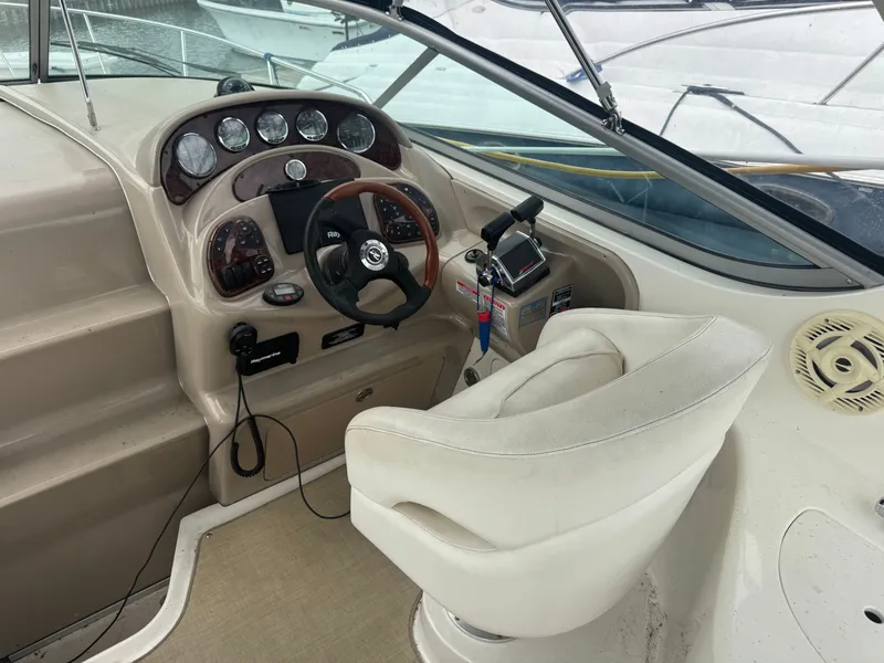 Slide: The Image of The cockpit of a 2005 Sea Ray Sundancer 280 with a white captain's chair and wood steering wheel. - 4