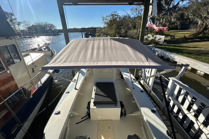 Slide: The Image of 2024 Custom Florida Flats CC boat docked, featuring a sunshade and scenic waterfront view. - 14