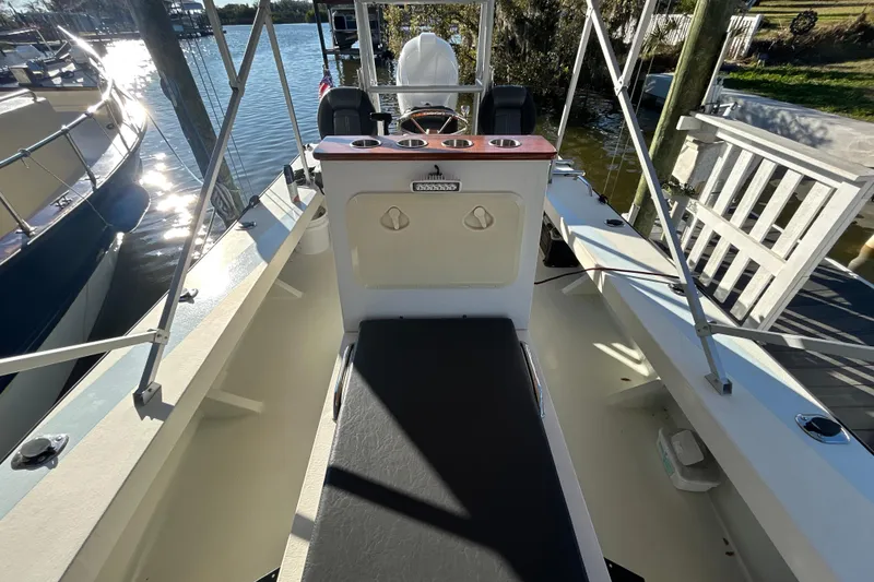 Slide: The Image of 2024 Custom Florida Flats CC boat interior with seating and console, docked by the water. - 15