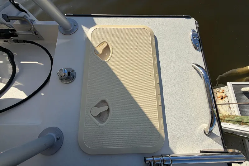 Slide: The Image of 2024 Custom Florida Flats CC boat deck with hatch and railing, docked by water. - 19