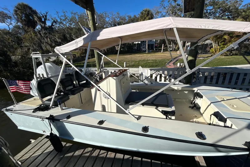 Slide: The Image of 2024 Custom Florida Flats CC boat docked with canopy and American flag. - 2