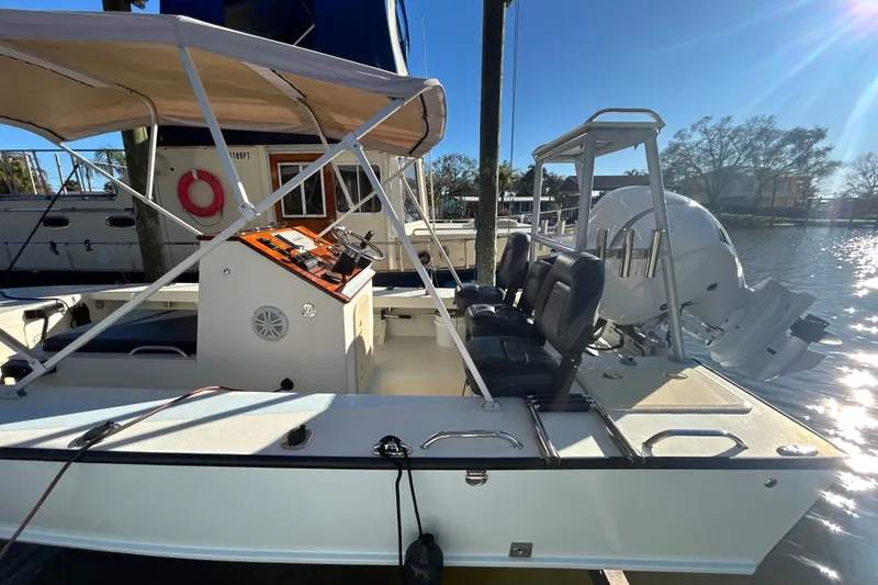 Slide: The Image of 2024 Custom Florida Flats CC boat docked, featuring seating and canopy. - 3