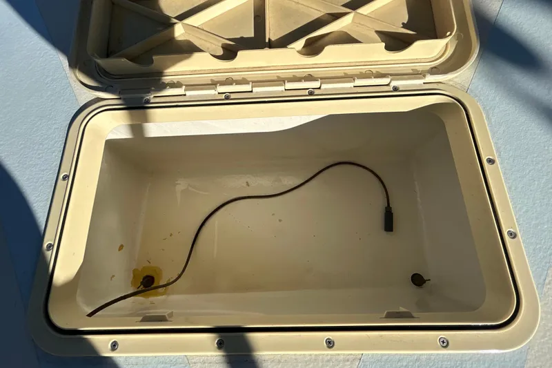 Slide: The Image of Open storage compartment in 2024 Custom Florida Flats CC boat, featuring a cable inside. - 31