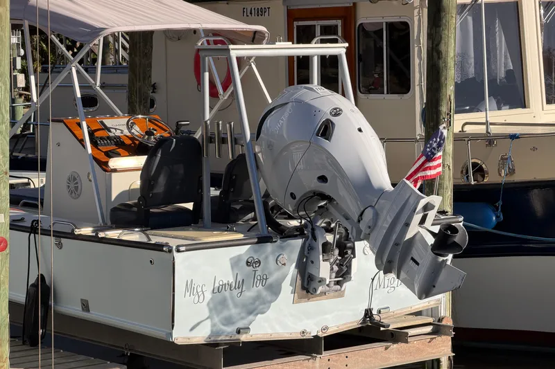Slide: The Image of 2024 Custom Florida Flats CC boat with outboard motor and American flag at dock. - 6
