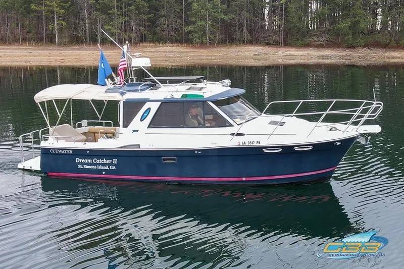 The Image of 2013 Cutwater C-28 boat, "Dream Catcher II," on calm water near a forested shoreline. - 0