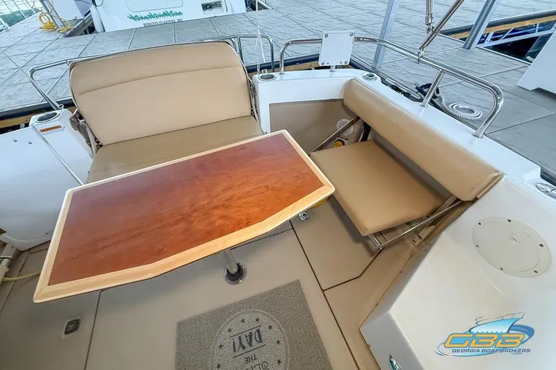 Slide: The Image of 2013 Cutwater C-28 boat interior with tan seating and wooden table in a marina setting. - 62