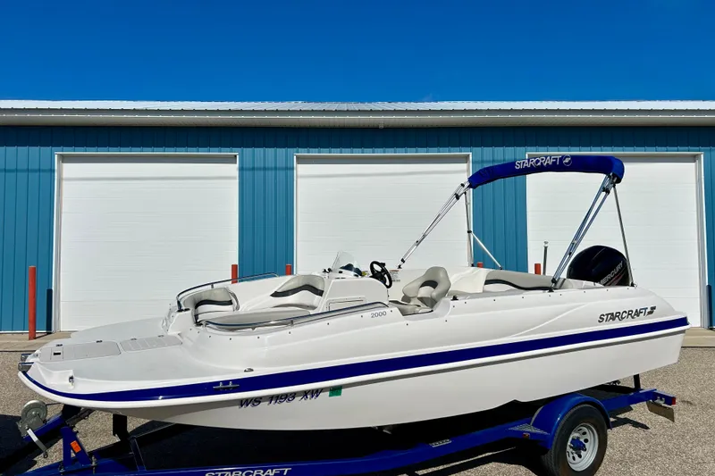 Slide: The Image of 2018 Starcraft 2000 OB Limited boat on trailer, parked in front of blue garage doors. - 3