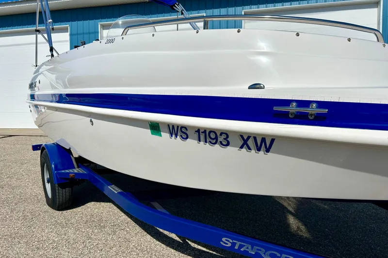 Slide: The Image of 2018 Starcraft 2000 OB Limited boat on trailer, white with blue accents, parked outdoors. - 6