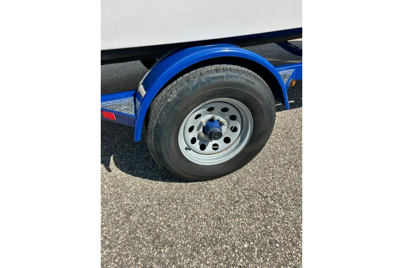 Slide: The Image of 2018 Starcraft 2000 OB Limited trailer wheel on asphalt, featuring blue fender. - 8