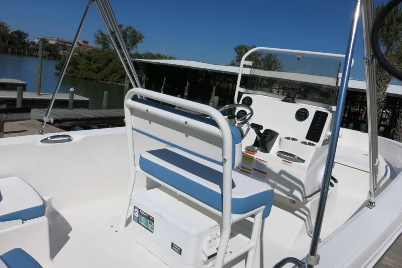 Slide: The Image of 2026 Robalo R160 Center Console boat interior with blue and white seating, docked by the water. - 21