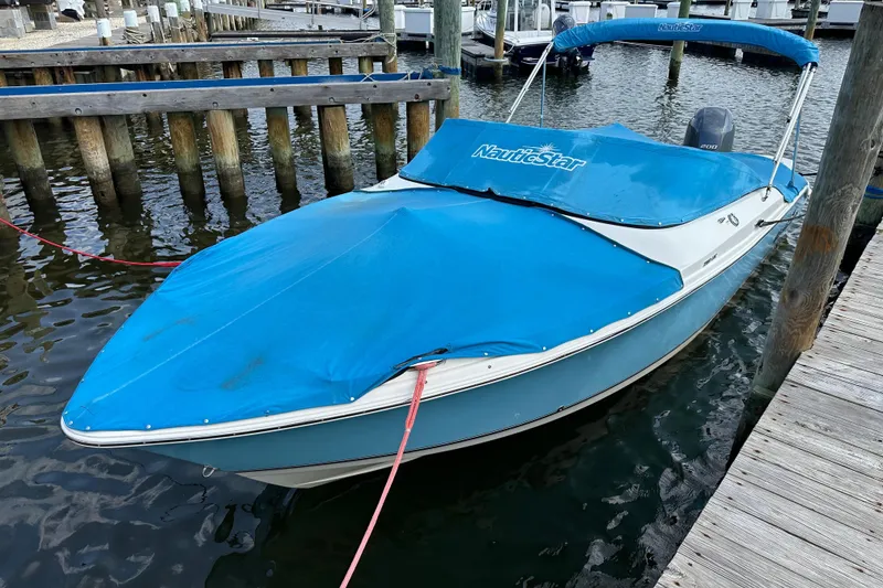 Slide: The Image of 2018 NauticStar 2302 Legacy Dual Console boat on blocks, blue hull, outdoor setting. - 24