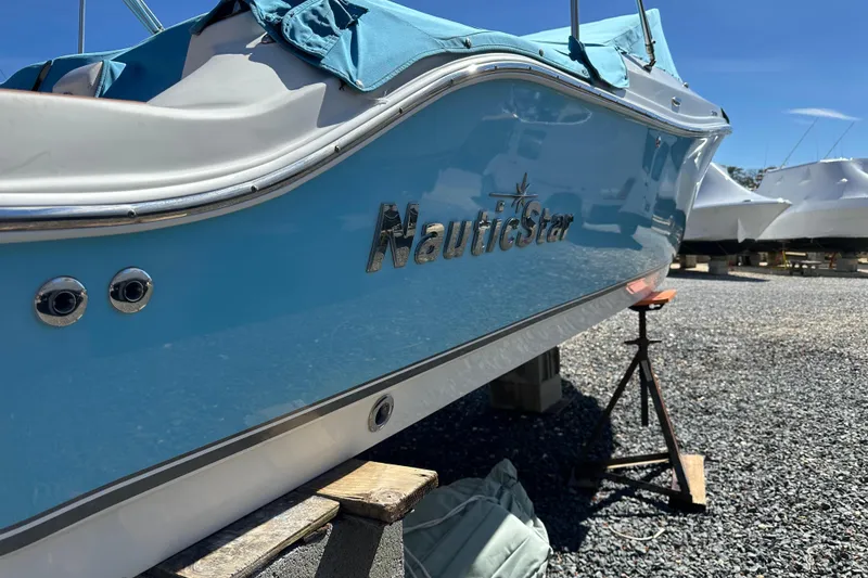 Slide: The Image of 2018 NauticStar 2302 Legacy Dual Console boat on a stand, blue hull, sunny day. - 28