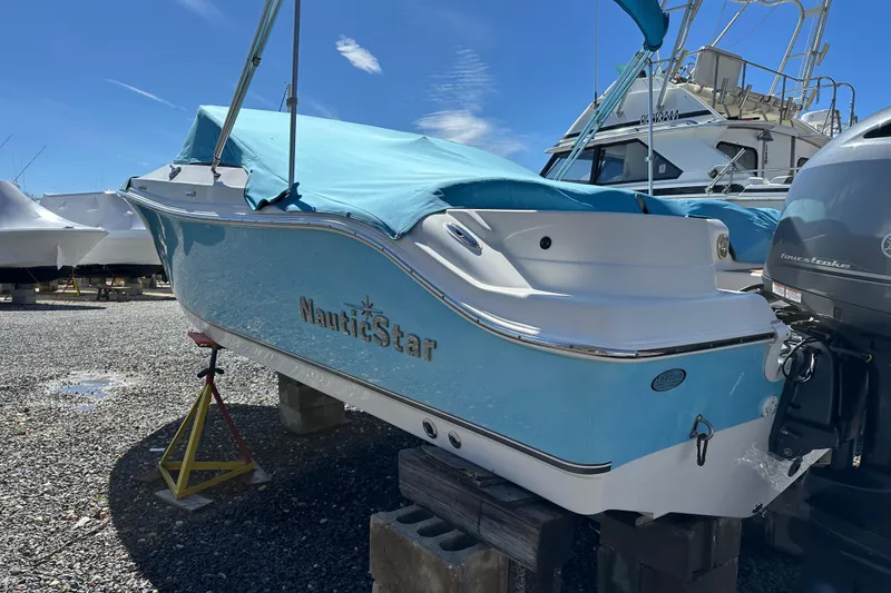 Slide: The Image of 2018 NauticStar 2302 Legacy Dual Console boat with blue cover, displayed outdoors. - 29