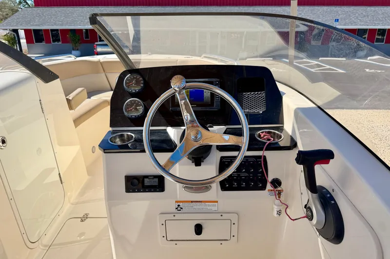 Slide: The Image of 2023 Scout 215 Dorado boat dashboard with steering wheel and controls. - 13