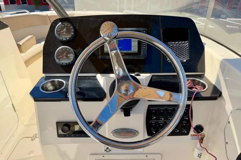 Slide: The Image of 2023 Scout 215 Dorado boat dashboard with steering wheel and navigation instruments. - 14