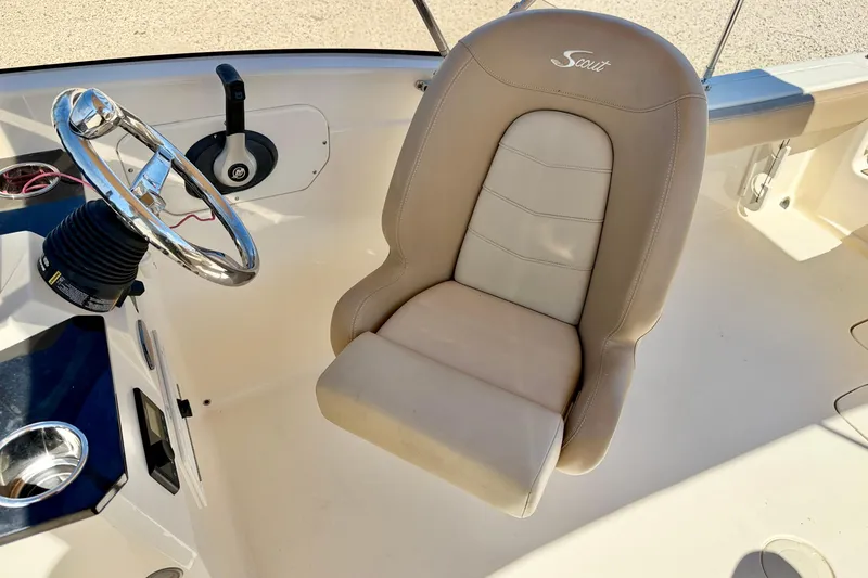 Slide: The Image of 2023 Scout 215 Dorado boat interior with steering wheel and beige captain's chair. - 19