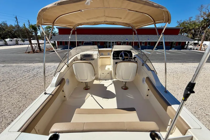 Slide: The Image of 2023 Scout 215 Dorado boat interior with canopy, beige seating, and steering console. - 22