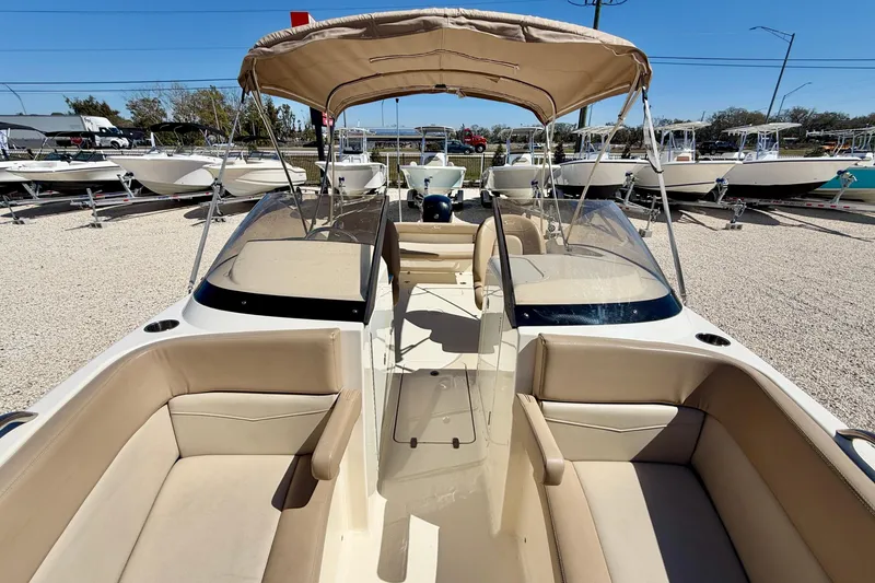 Slide: The Image of 2023 Scout 215 Dorado boat with beige seating and canopy, displayed outdoors. - 27