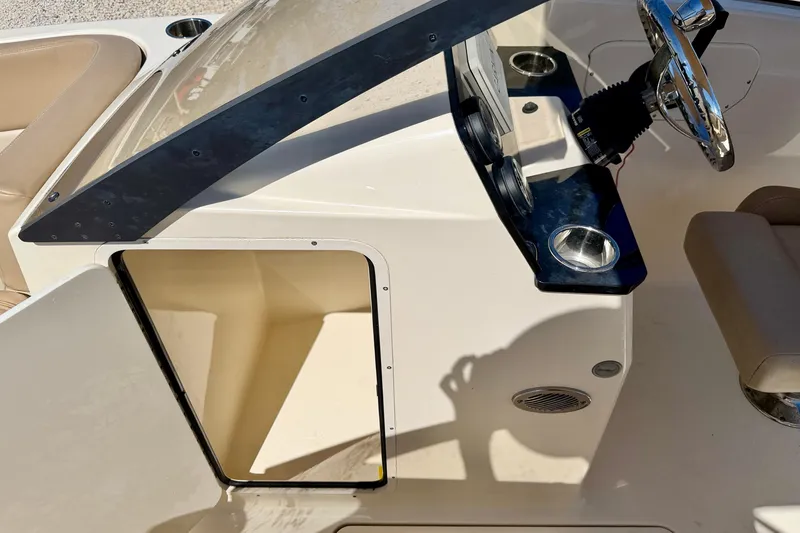 Slide: The Image of 2023 Scout 215 Dorado boat interior with steering wheel and open storage compartment. - 28