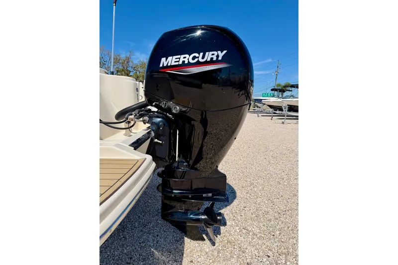 Slide: The Image of 2023 Scout 215 Dorado with Mercury outboard motor, parked on gravel under clear blue sky. - 32